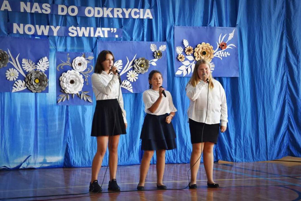 Uczennice klasy piątej i szóstej spiewają piosenkę podczas apelu.  