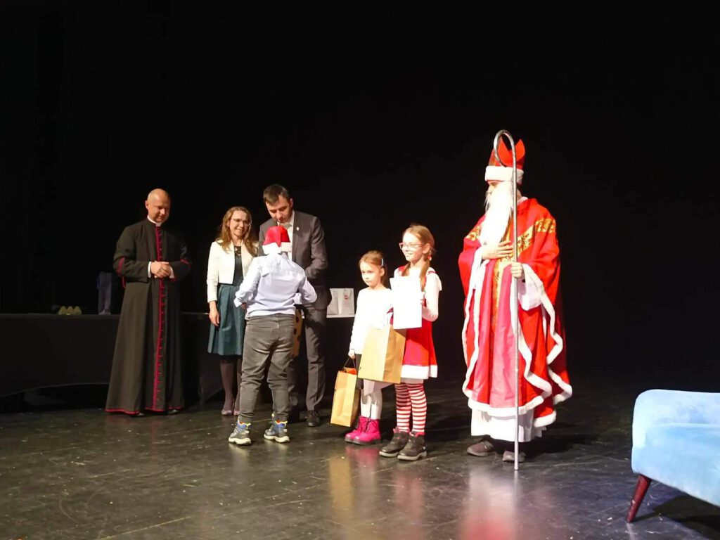 Na zdjęciu laureaci konkursu plastycznego ramach Dni ze Świętym Mikołajem pod hasłem "Święty Mikołaj biskup - patron Głogowa" stoją na scenie i odbierają nagrody za zajęte miejsca. 