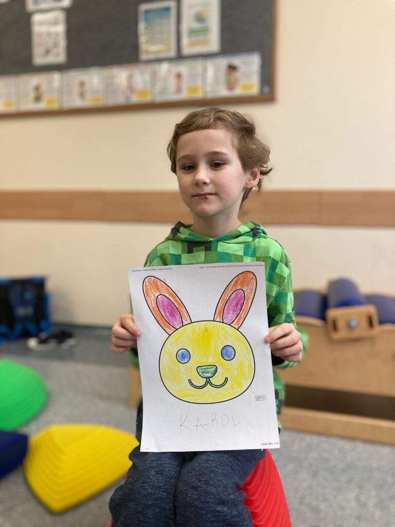 Uczeń prezentuje swojego pokolorowanego królika. 