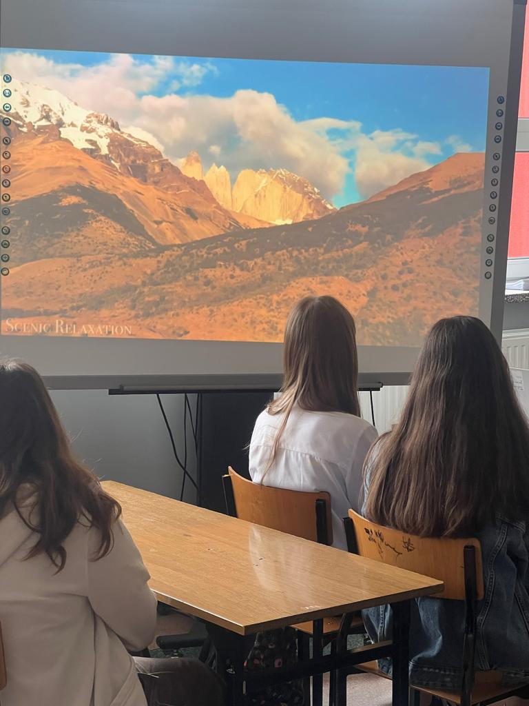 Na zdjęciu widać trzy dziewczynki, które oglądają film o pięknych krajobrazach Chile. 