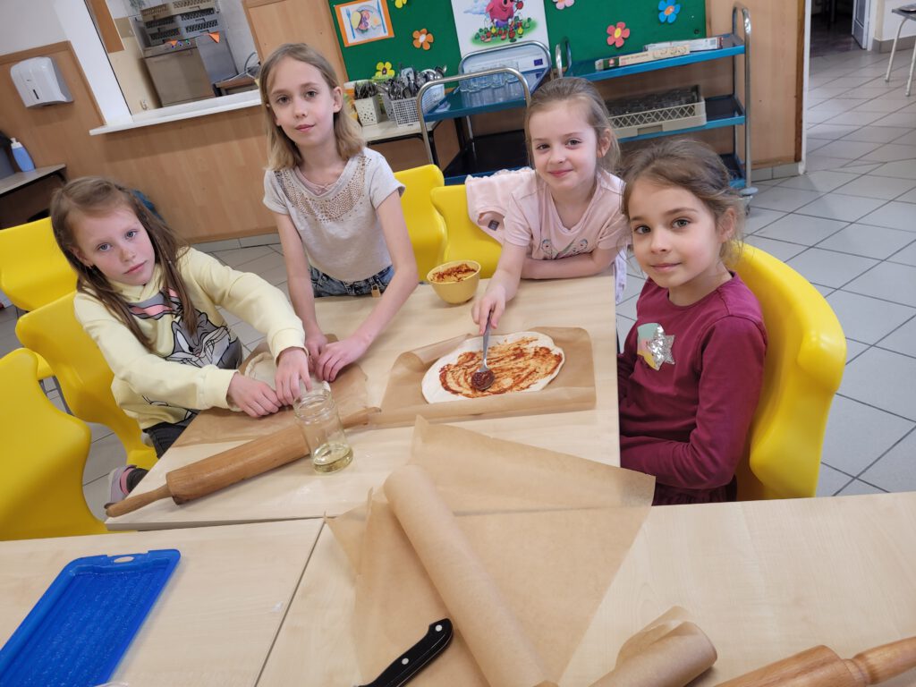 Pizza na zajęciach świetlicowych. Na zdjęciu dziewczynki komponują wlaną pizzę.