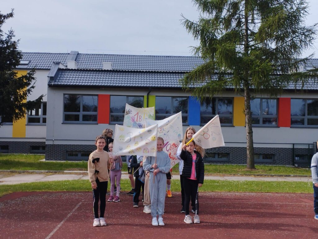 Mini olimpiada  w ramach realizacji projektu „Z Fundacją PZU po lekcjach „Popołudnia z Uśmiechem, czyli nudzie mówimy stop”. Na zdjęciu widać uczniów, którzy prezentują swoje flagi klasowe na mini olimpiadę. 