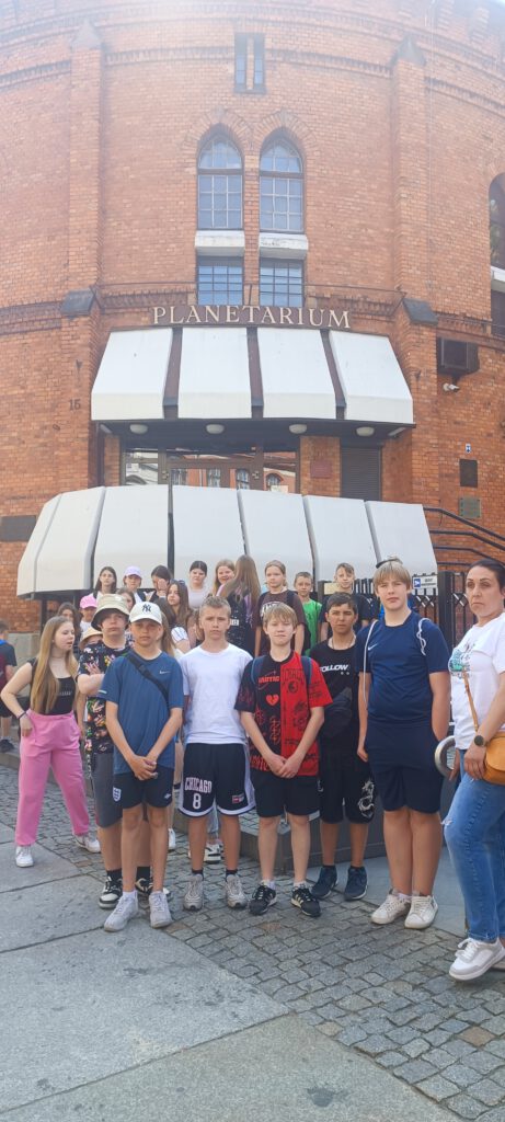 Dwudniowa wycieczka do Biskupina i Torunia w ramach programu "Poznaj Polskę". Uczniowie stoją całą grupą przed budynkiem Planetarium w Toruniu. 