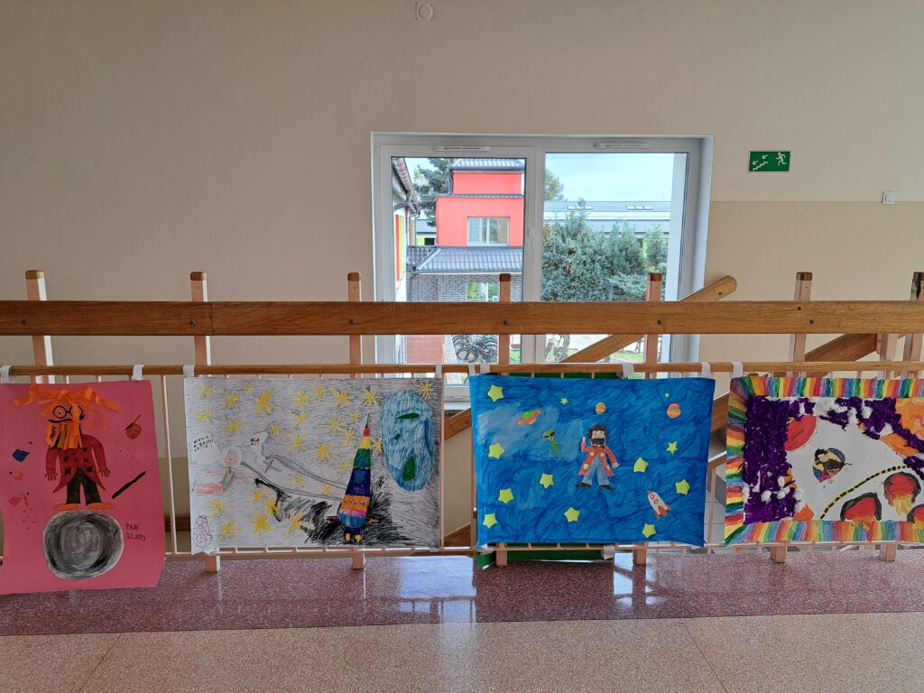 Zdjęcie przedstawia kolorowe prace plastyczne wykonane w ramach zajęć "Kosmos w literaturze". Prace przedstawiają Pana Kleksa i ozdabiają one szkolny korytarz.