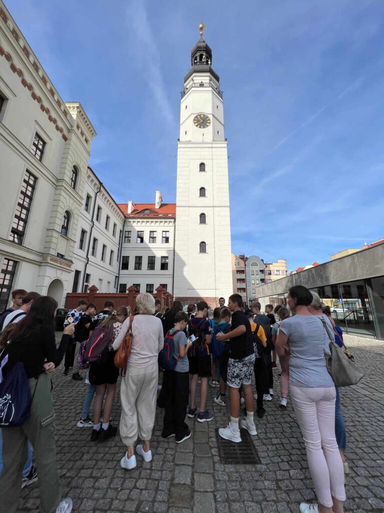 Wycieczka krajoznawczo-historyczna do Głogowa. Uczniowie stoją przy wieży ratuszowej. 