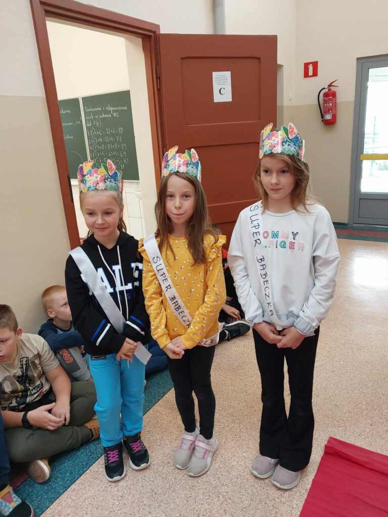 Szkole obchody Międzynarodowego  Dnia Dziewczynek. Na zdjęciu trzy dziewczynki z klas 1-3 w koronach na głowie po otrzymaniu tytułu "Super Babeczka".