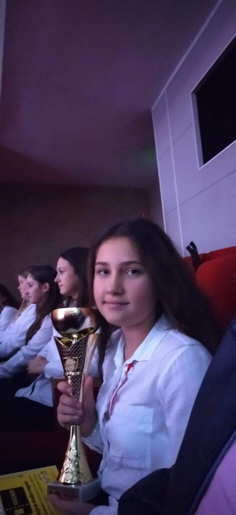 Gala Laureatów XII Międzypowiatowego Festiwalu Piosenki Patriotycznej "𝗩𝗜𝗩𝗔𝗧 𝗣𝗢𝗟𝗢𝗡𝗜𝗔". Na zdjęciu uczennica klasy 6 trzyma puchar w ręku za zdobycie I miejsca. 