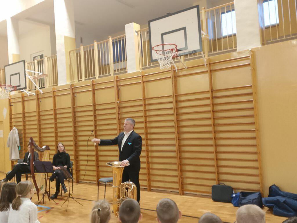 Koncert filharmonii- harfa i tuba.  Na zdjęciu pan pokazuje uczniom jak zbudowana jest tuba. 