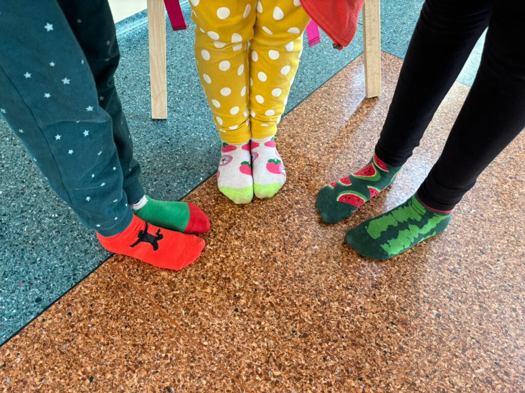Dzień Kolorowej Skarpetki . Na zdjęciu  nogi uczniów z kolorowymi skarpetkami. 