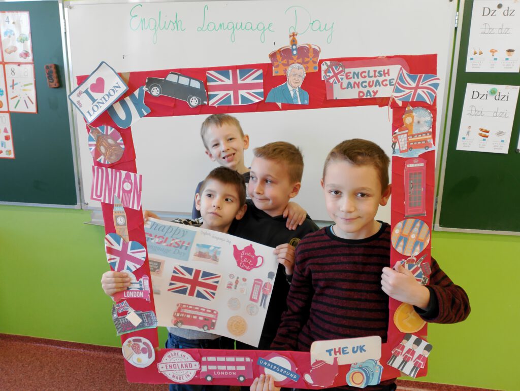 Dzień Języka Angielskiego. Na zdjęciu czterech chłopców klasy czwartej pozują do zdjęcia  w foto ramce z elementami - symbolami Londynu i Wielkiej Brytanii. 