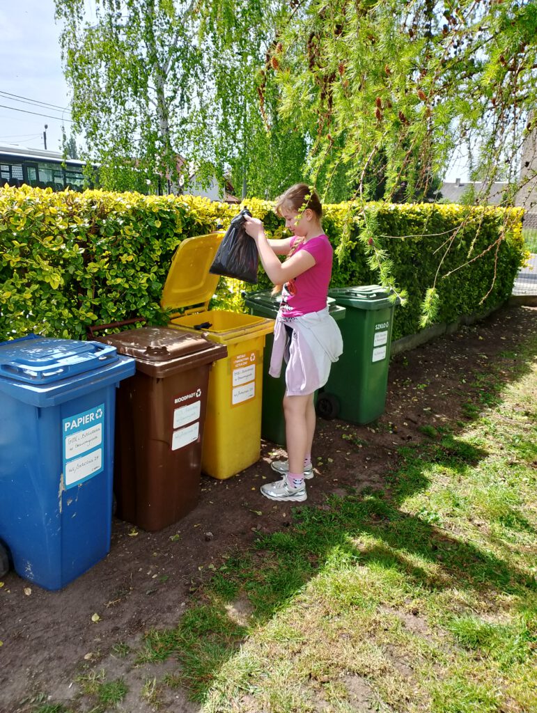 Dzień Ziemi "Planeta kontra plastik". Na zdjęciu uczennica wyrzuca do pojemnika na plastik zebrane śmieci. 