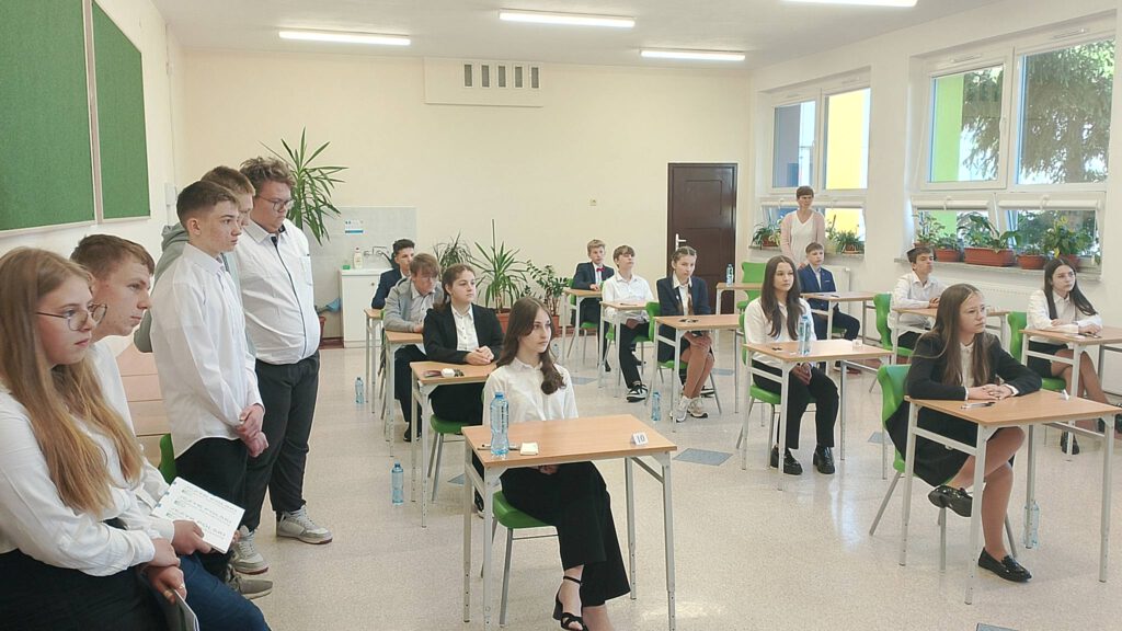Egzamin ósmoklasisty. Na zdjęciu uczniowie klasy ósmej ubrani na galowo siedzą w klasie i czekają na rozpoczęcie egzaminu.  