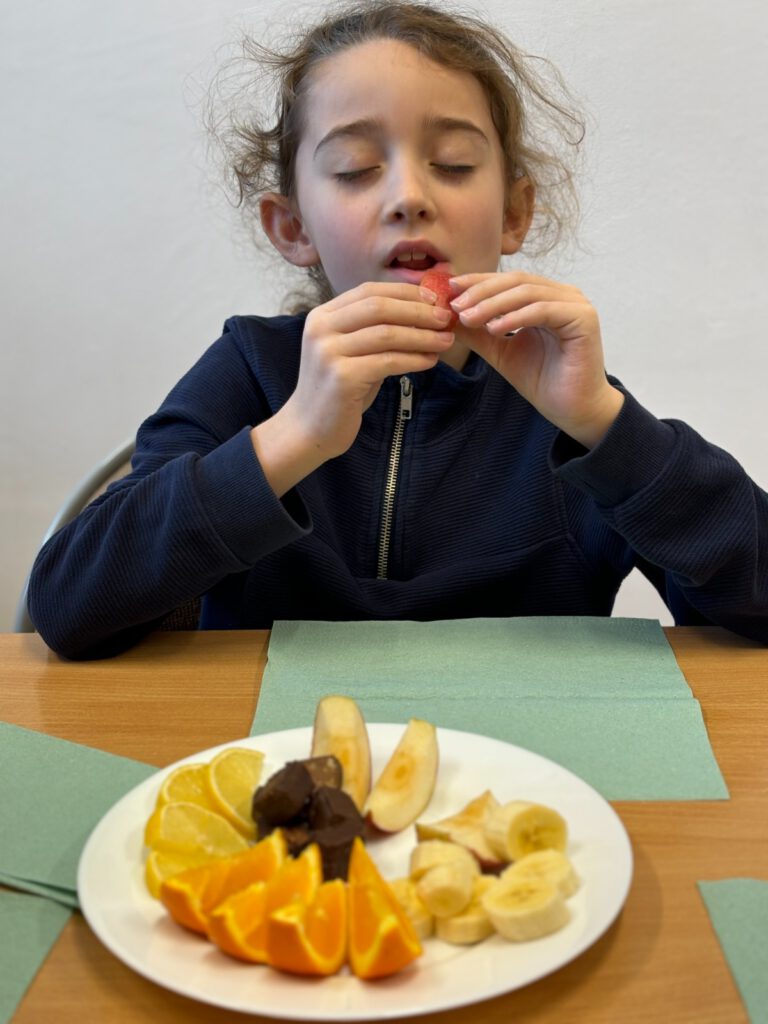 Projekt "Gramy zmysłami"- styczeń- akademia smaku. Na zdjęciu uczeń z zamkniętymi oczami próbuje owoców o różnych smakach. 