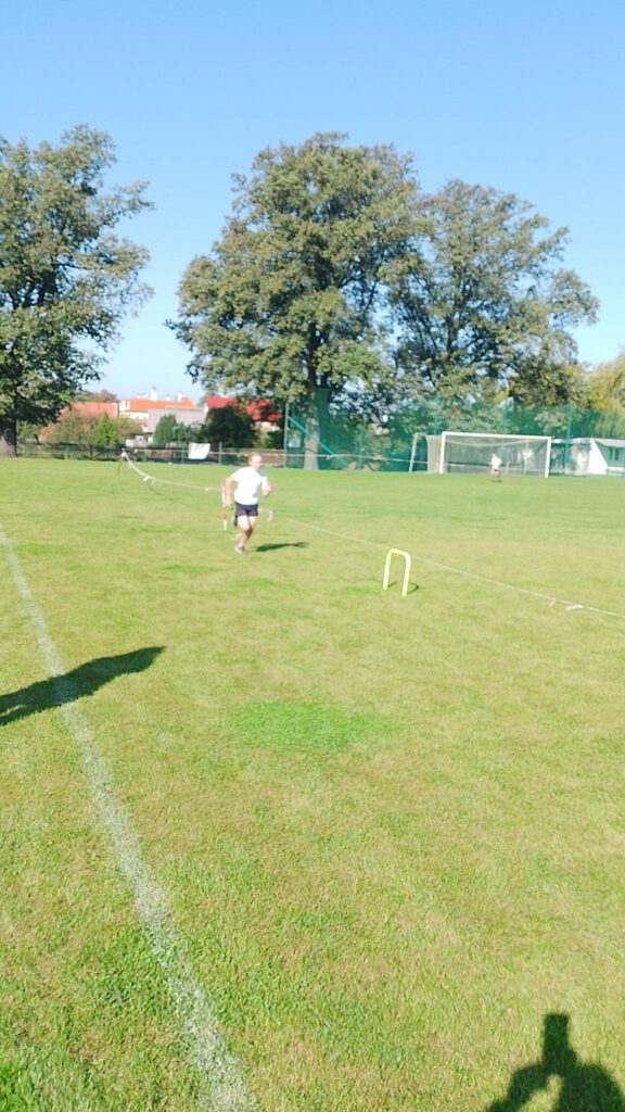 Ogórkowa sztafeta- szkolna akcja sportowa. Na zdjęciu biegnie chłopiec po zielnym boisku. 