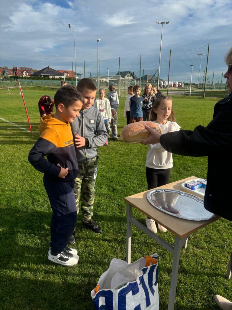 Dzieci odbierają chleb i masło po zakończeniu biegu.