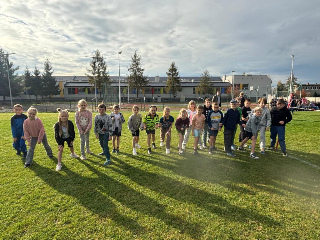 Nas zdjęciu uczniowie klas 1-3 stoją na starcie biegu, przygotowują się do rozpoczęcia biegu.  