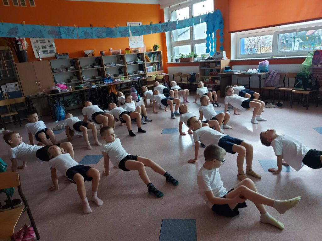 Moving Schools Challenger – aktywna szkoła. Uczniowie w strojach sportowych wykonują ćwiczenie „stolik”.