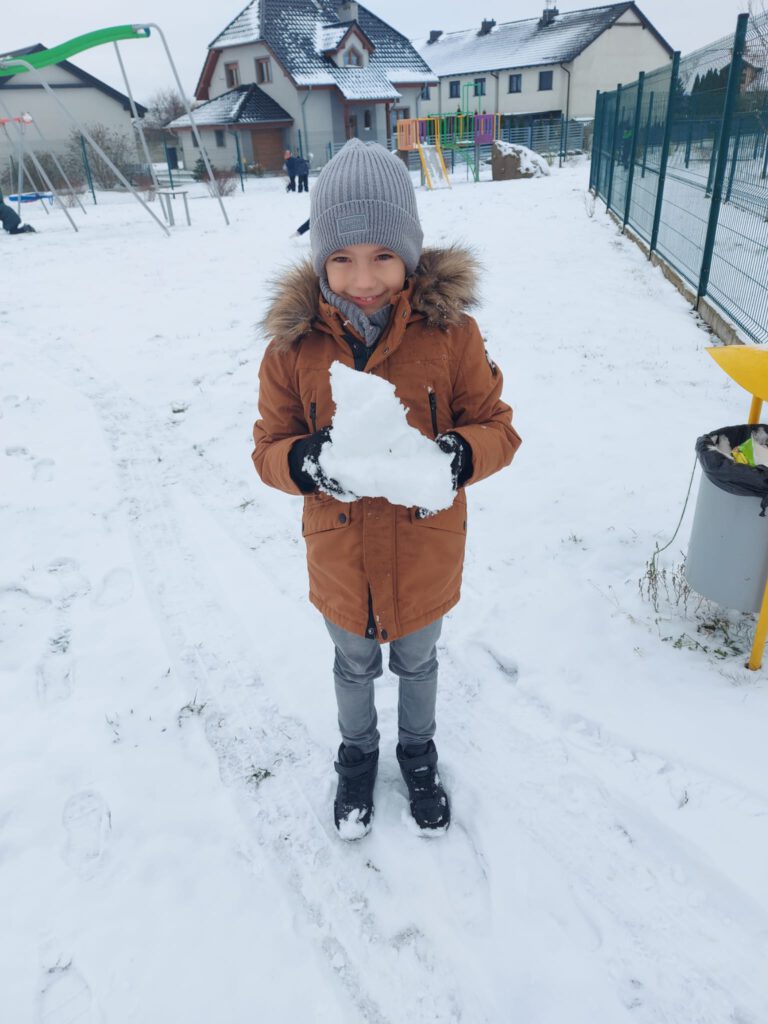 Moving Schools Challenger – przegląd stycznia. Na zdjęciu uśmiechnięty uczeń trzyma duży kawałek śniegi. 