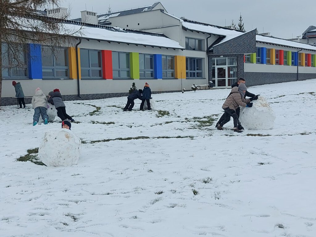 Moving Schools Challenger – przegląd stycznia. Na zdjęciu  uczniowie bawią się na śniegu, toczą kile śniegowe. 