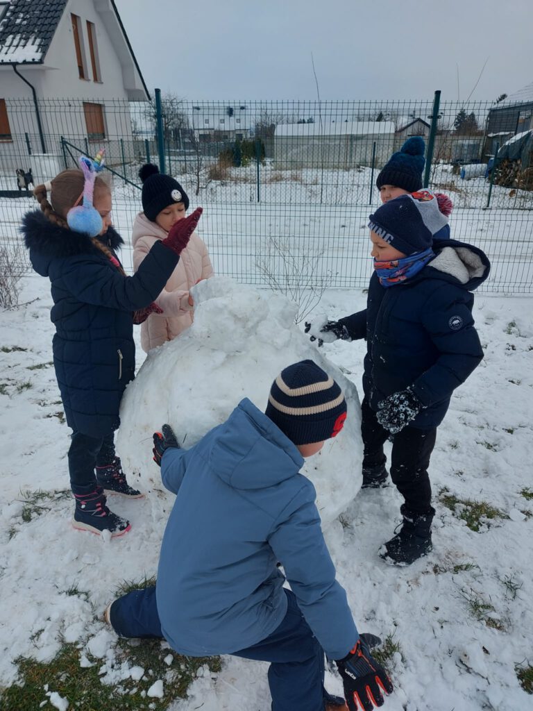 Moving Schools Challenger – przegląd stycznia. Na zdjęciu uczniowie  bawią się na śniegu, lepią dużą kulę śniegu. 