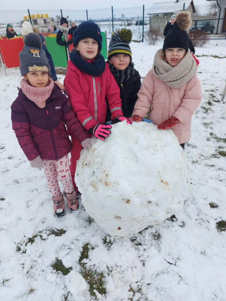 Moving Schools Challenger – przegląd stycznia. Na zdjęciu cztery uczennice  bawią  się na śniegu, stoją obok wielkiej kuli śniegu. 