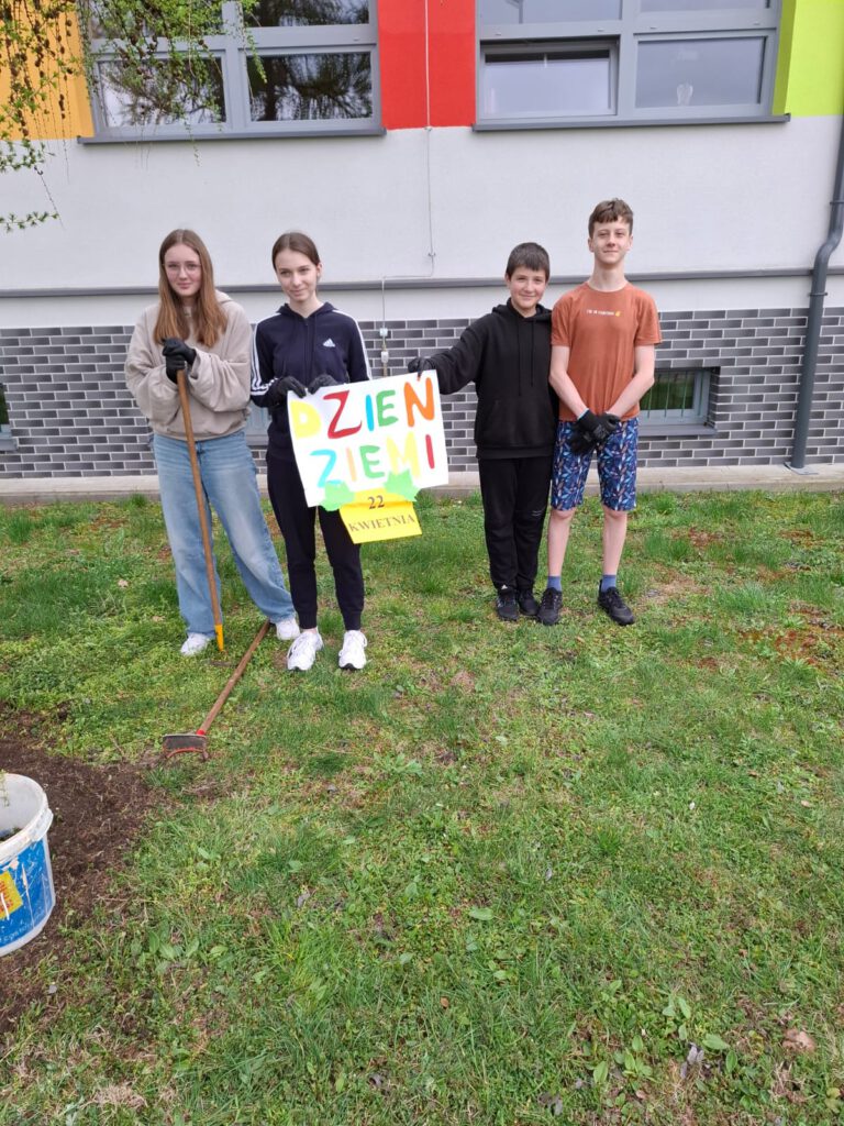 Na zdjęciu uczniowie klasy 7a biorący aktywny udział w szkolnej akcji obchodów Dnia Ziemi, trzymający w rękach plakat z napisem 22 kwietnia - Dzień Ziemi.
