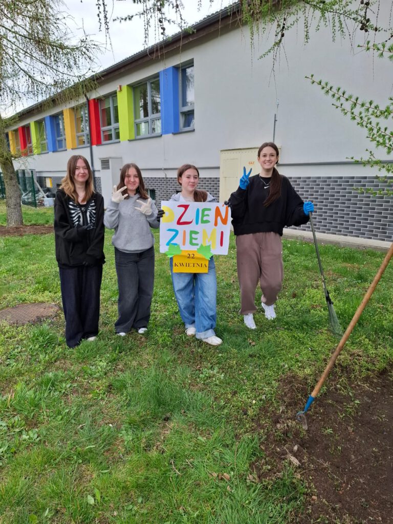 Na zdjęciu uczennice klasy 7a biorące aktywny udział w szkolnej akcji obchodów Dnia Ziemi, trzymający w rękach plakat z napisem 22 kwietnia - Dzień Ziemi.
