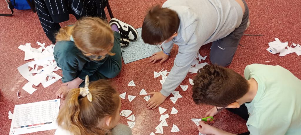 Projekt Active Sister Schools. Na zdjęciu uczniowie wycinają z papieru układankę.