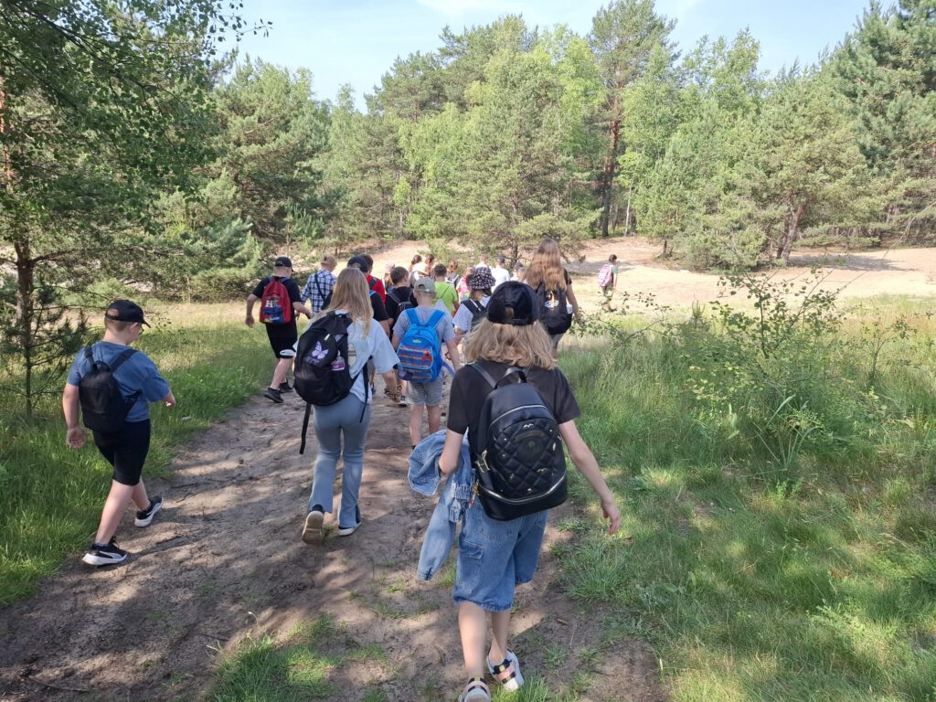Wyjazdy w ramach akcji „Poznaj swój park krajobrazowy”. Na zdjęciu uczestniczy warsztatów maszerujący na wydmy śródlądowe.