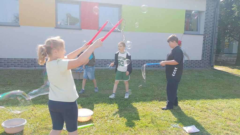 Piknik "Powitanie lata". Na zdjęciu uczniowie robią bańki mydlane.