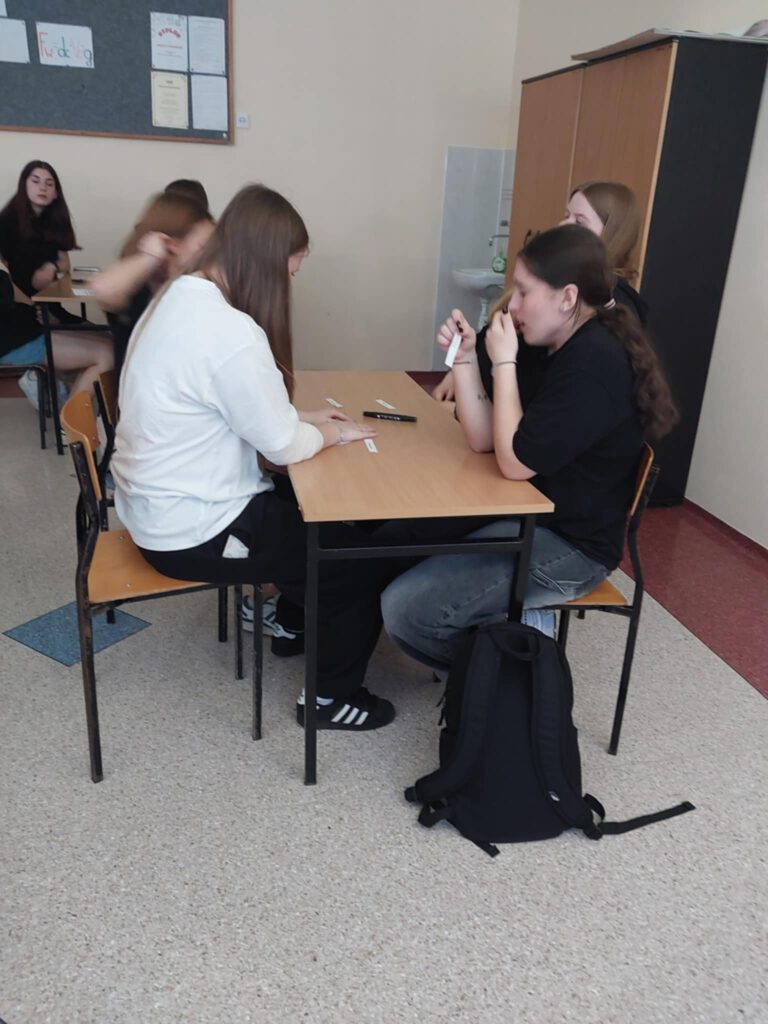 Warsztaty z doradztwa zawodowego. Na zdjęciu uczniowie klas ósmych siedzą w ławkach i wykonują zadanie. 