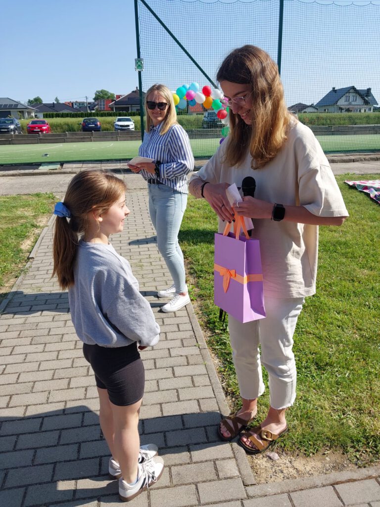 Rozstrzygnięcie akcji „Zagadka Dnia”. Wychowawczyni świetlicy wręcza nagrodę Mistrzyni Zagadek w kategorii klas 1-3.