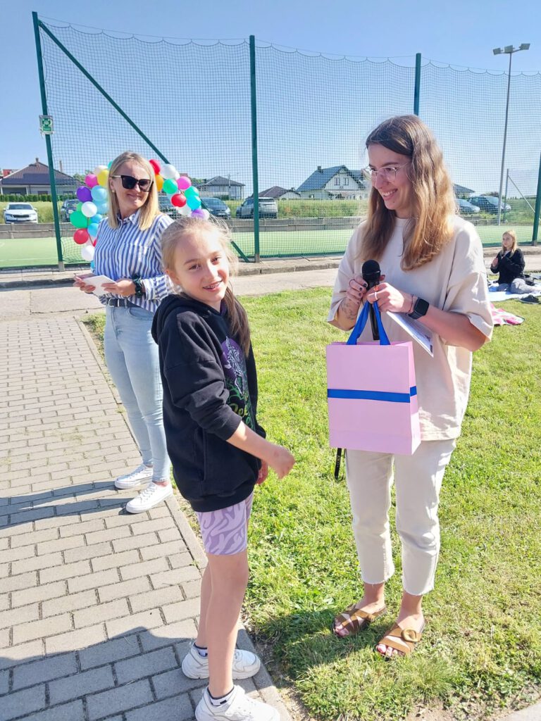 Rozstrzygnięcie akcji „Zagadka Dnia”. Wychowawczyni świetlicy wręcza nagrodę I Wicemistrzyni Zagadek w kategorii klas 1-3.