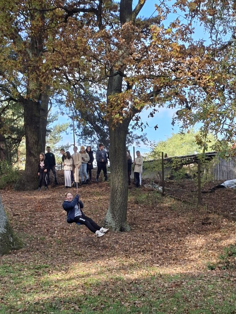 Zdjęcie przedstawia ucznia zjeżdżającego na tyrolce. Uczeń trzyma się dwoma rękami liny.