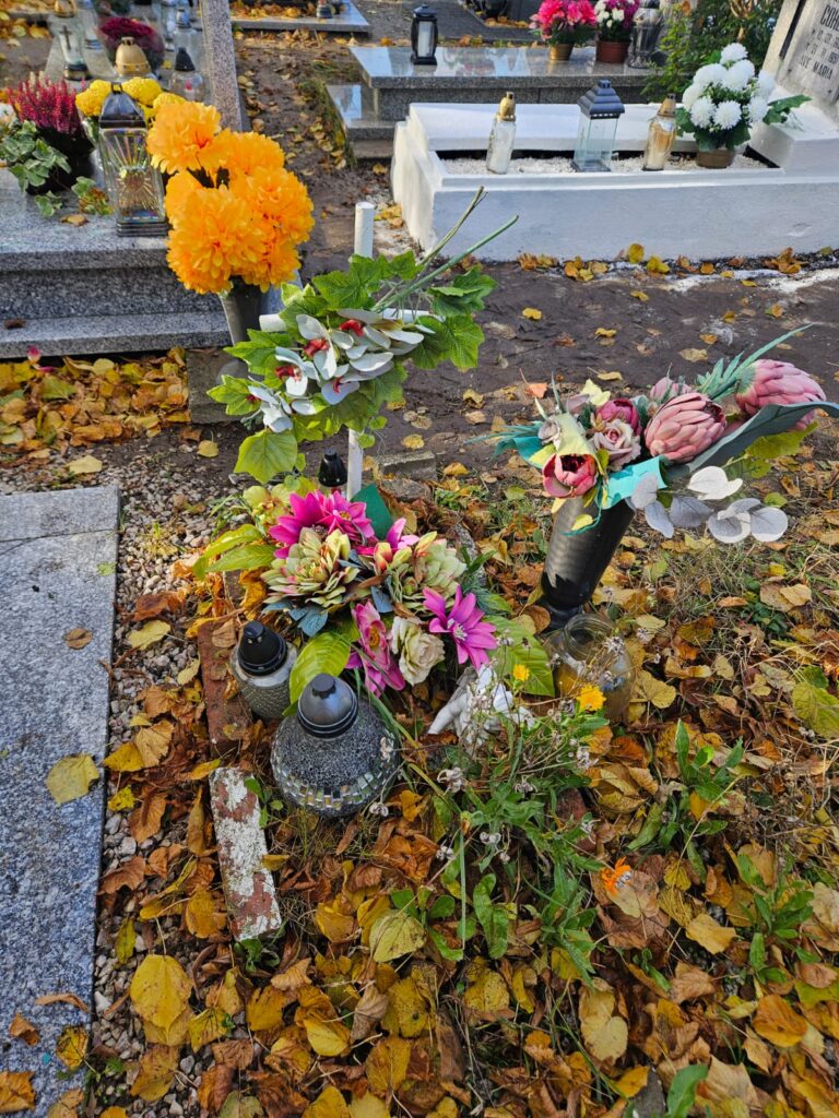 Ocalić od zapomnienia, czyli sprzątamy opuszczone groby. Na zdjęciu mały grób. Widoczny  stary, drewniany krzyż i sztuczne bukiety kwiatów. Z lewej strony stary znicz .