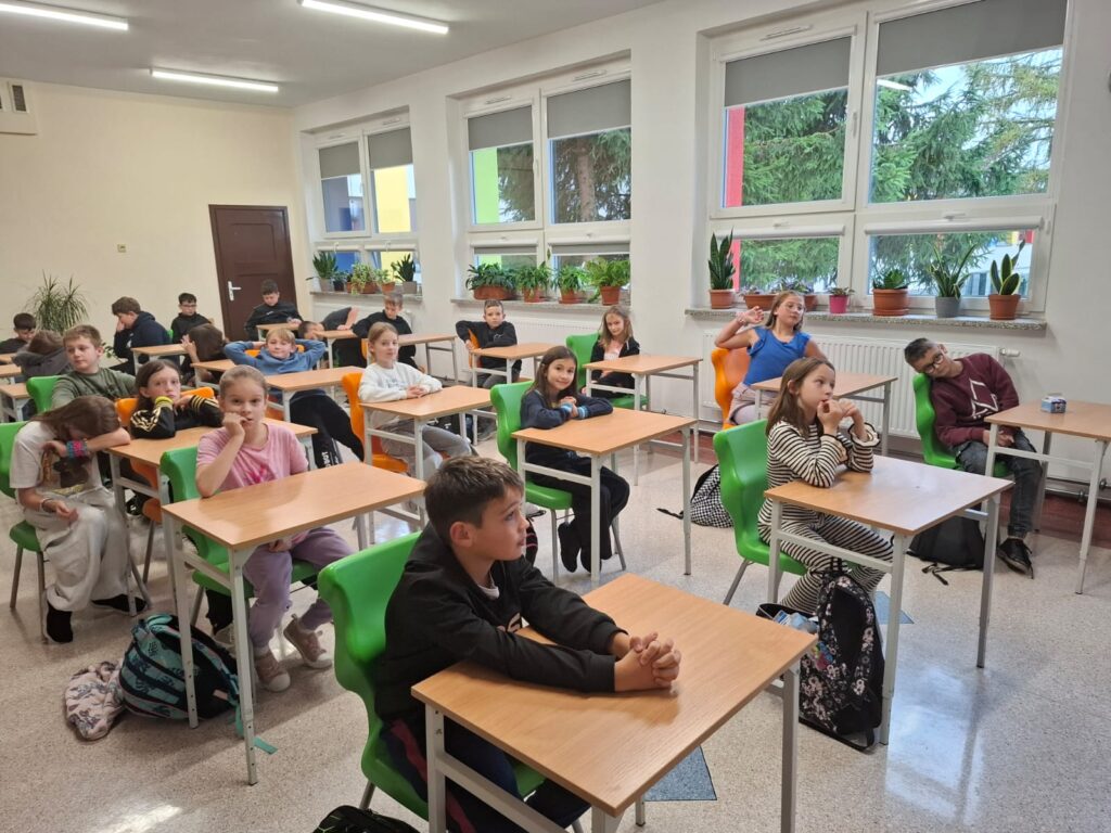 Spotkania ze specjalistami w ramach zajęć z edukacji zdrowotnej i przyrodniczej. Na zdjęciu uczniowie klasy czwartej i piątej, siedzą w ławeczkach i słuchają prelekcji o zdrowym odżywianiu.