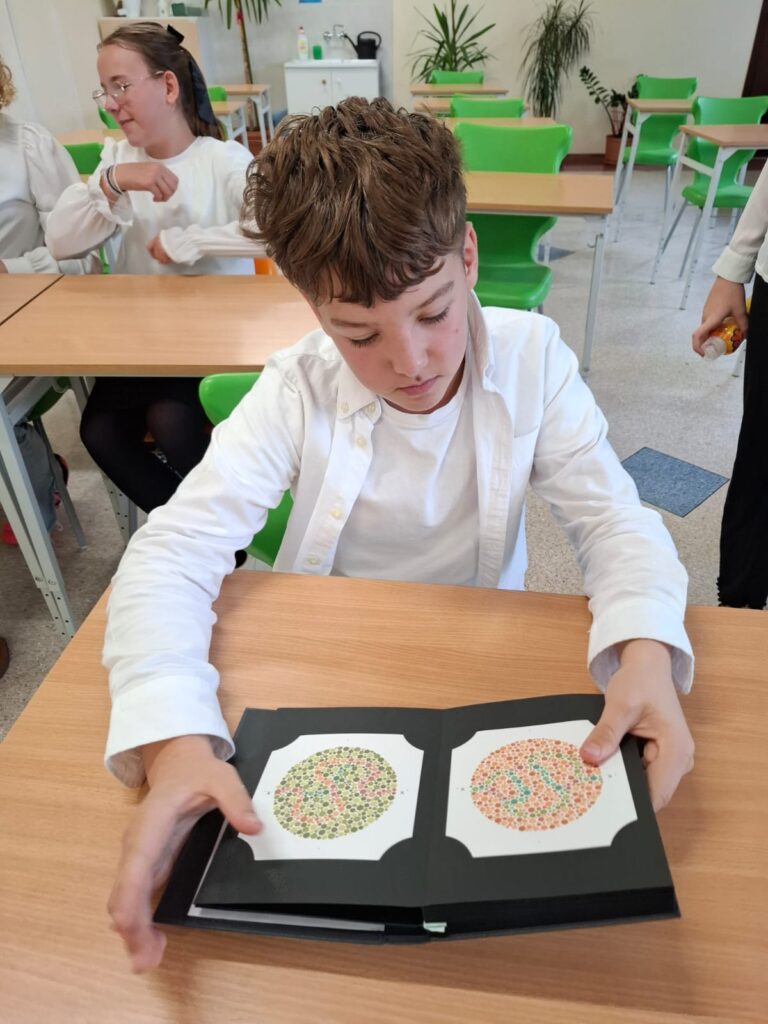 Spotkania ze specjalistami w ramach zajęć z edukacji zdrowotnej i przyrodniczej. Na zdjęciu uczeń siedzi w ławce i trzyma w rękach książkę.