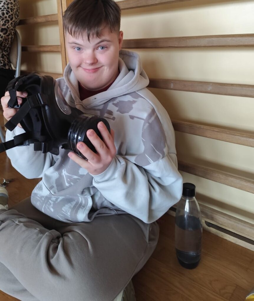 Edukacja z wojskiem. Na zdjęciu uczeń trzyma w rękach maskę gazową.