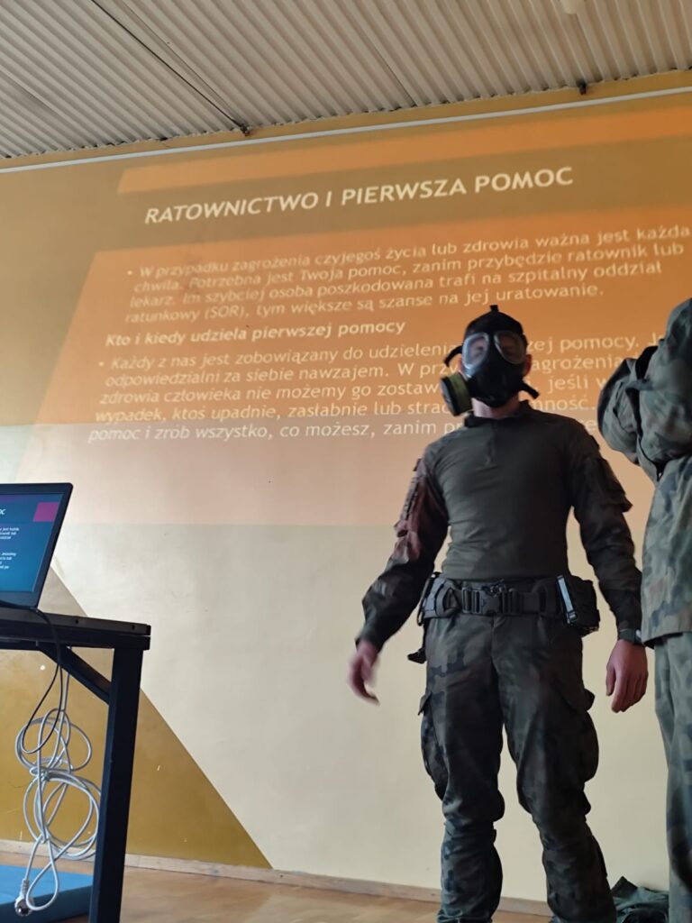 Edukacja z wojskiem. Na zdjęciu żołnierz w masce gazowej na twarzy.