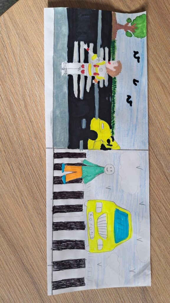 Odblaskowa szkoła 2025- komiksy uczniów. Na zdjęciu komiksy wykonane ręcznie prze uczniów w formie obrazkowej na temat bezpieczeństwa w ruchu drogowym, przy przechodzeniu przez jednię i stosowania zasad ruchu drogowego. 