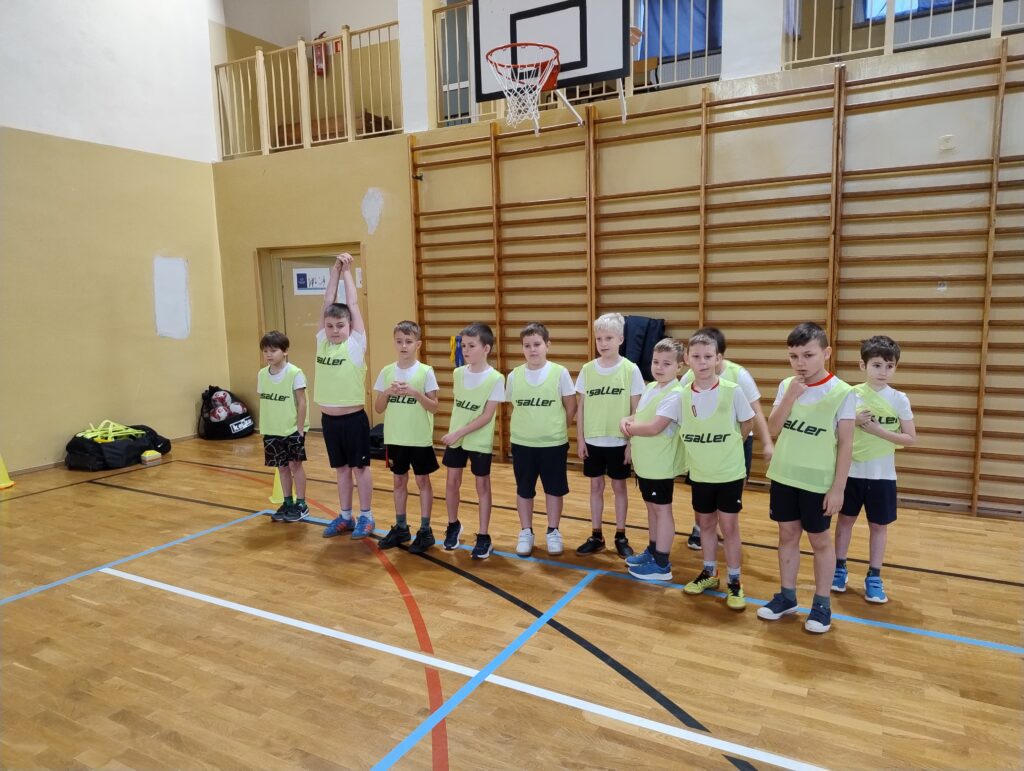 zDolnośląskie Dzieciaki.  Na zdjęciu uczniowie z klasy drugiej, ubrani z kamizelki seledynowe pozują na zdjęcia. Za chłopcami drewniane drabinki.