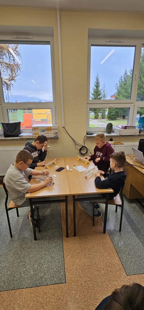 Na zdjęciu widzimy 4 chłopców przy stoliku grających w Rummikuba.
