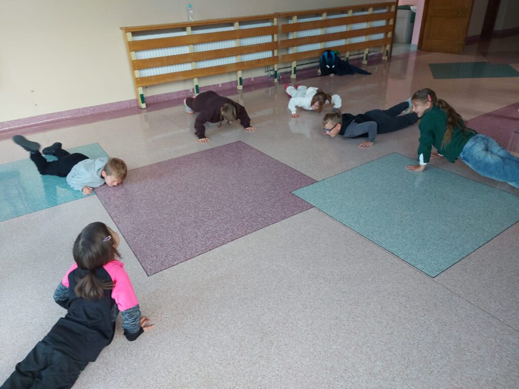 Zajęcia na świetlicy- poranny rozruch. Dzieci wykonują ćwiczenia gimnastyczne.