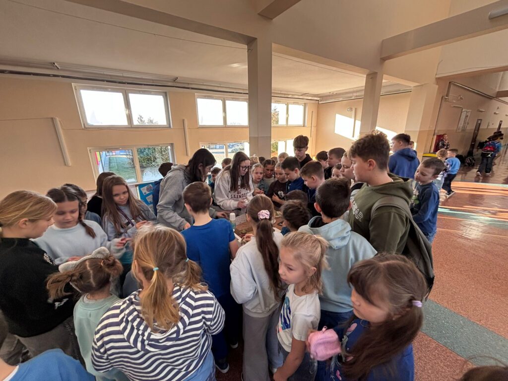 Światowy Dzień Praw Dziecka.   Na zdjęciu widać uczniów klas 1-8 podczas akcji sprzedaży szkolnych galaretek. W tle widać szkolny korytarz.