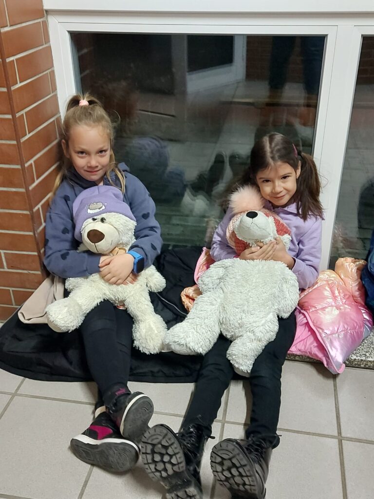 Dziewczynki trzymają ubrane w czapeczki pluszowe misie.