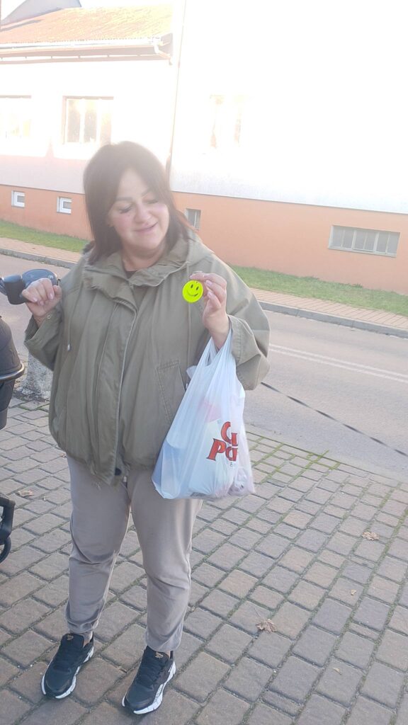 Odblaskowa Szkoła 2025- akcja rozdawania odblasków. Na zdjęciu mieszkanka Gaworzyc pokazuje otrzymany odblask- buźkę. 