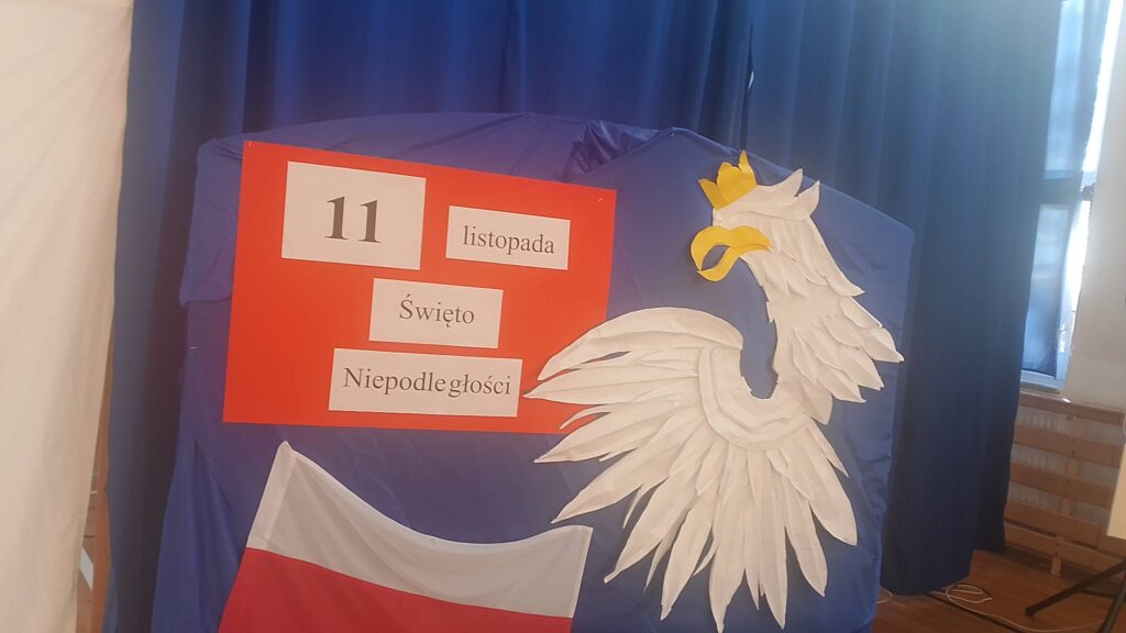 Apel z okazji Święta Niepodległości. Na zdjęciu dekoracja patriotyczna: biały orzeł, flaga Polski, i i napis na czerwonym brystolu: 11 listopada Święto Niepodległości.