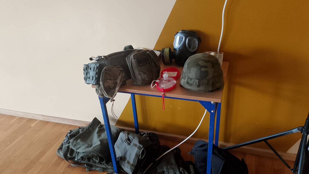 Edukacja z wojskiem. Na zdjęciu hełmy wojskowe, maski gazowe i inne wyposażenie żołnierza.