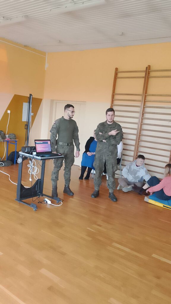 Edukacja z wojskiem. Na zdjęciu dwóch żołnierzy, którzy przekazują uczniom wiedzę na temat działań proobronnych.