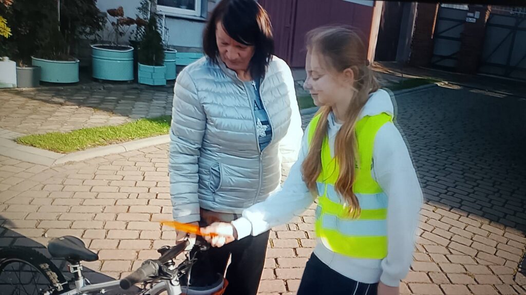 Odblaskowa Szkoła 2025- akcja rozdawania odblasków. Na zdjęciu uczennica  jest zadowolona, że wręczyła odblask starszej pani. 
